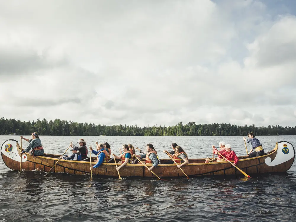 Un groupe de personnes pagayant dans une reproduction d'un canot de voyageur historique dans le parc Quetico.